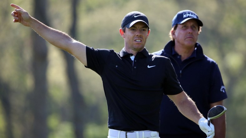 May 17, 2019; Bethpage, NY, USA; Rory McIlroy reacts after his shot from the 12th tee as Phil Mickelson (right) looks on during the second round of the PGA Championship golf tournament at Bethpage State Park - Black Course. Mandatory Credit: Peter Casey-USA TODAY Sports