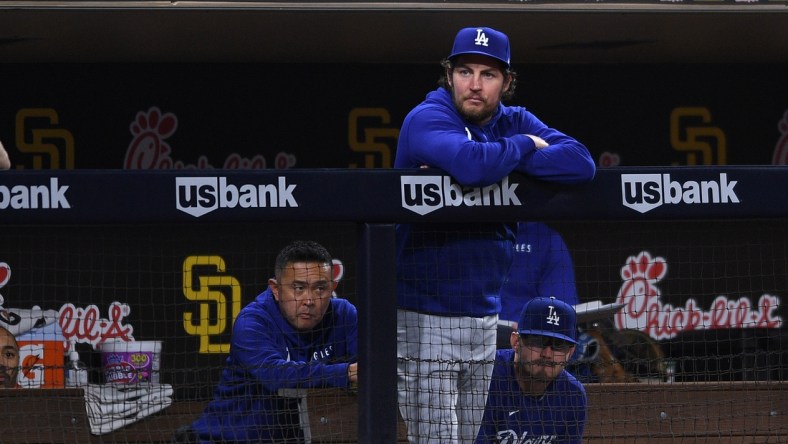 Jun 22, 2021; San Diego, California, USA; Los Angeles Dodgers starting pitcher Trevor Bauer (top) looks on from the dugout during the fifth inning against the San Diego Padres at Petco Park. Mandatory Credit: Orlando Ramirez-USA TODAY Sports