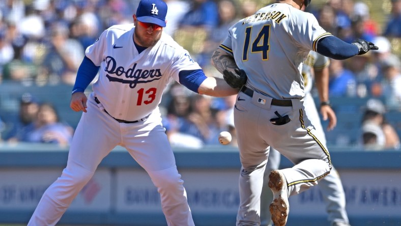 Oct 3, 2021; Los Angeles, California, USA;  Los Angeles Dodgers first baseman Max Muncy (13) makes a tag against Milwaukee Brewers second baseman Jace Peterson (14) on a throw from Dodgers shortstop Trea Turner (not pictured) in the third inning at Dodger Stadium. Muncy left the game with an apparent injury to his left arm. Mandatory Credit: Jayne Kamin-Oncea-USA TODAY Sports