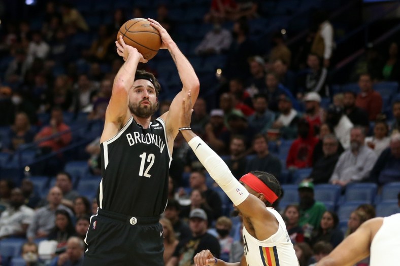 Nov 12, 2021; New Orleans, Louisiana, USA; Brooklyn Nets forward Joe Harris (12) attempts a jump shot while defended by New Orleans Pelicans guard Devonte' Graham (4) during the first quarter at the Smoothie King Center. Mandatory Credit: Chuck Cook-USA TODAY Sports