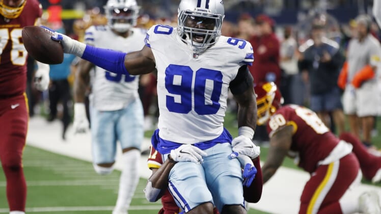 Dec 26, 2021; Arlington, Texas, USA; Dallas Cowboys defensive end Demarcus Lawrence (90) returns an interception for a touchdown in the first quarter against the Washington Football Team at AT&T Stadium. Mandatory Credit: Tim Heitman-USA TODAY Sports