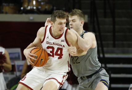 Mar 1, 2022; Norman, Oklahoma, USA; Oklahoma Sooners forward Jacob Groves (34) is defended by West Virginia Mountaineers guard Sean McNeil (22) on a drive to the basket during the first half at Lloyd Noble Center. Mandatory Credit: Alonzo Adams-USA TODAY Sports