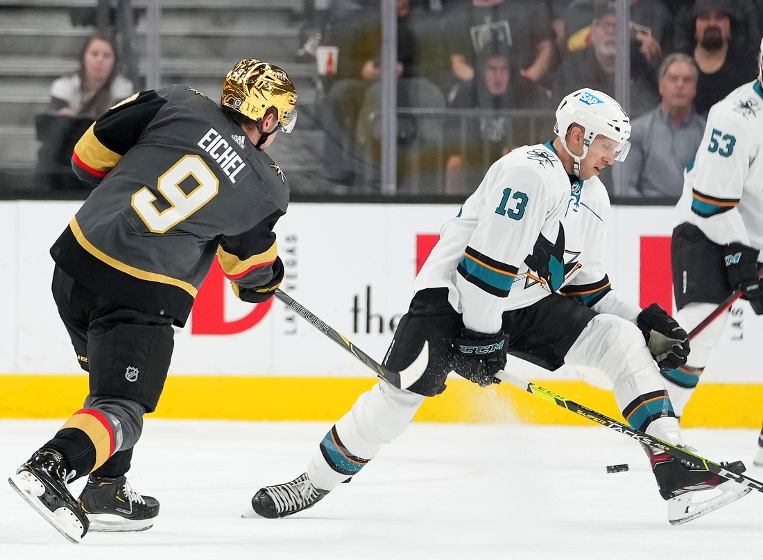 Mar 1, 2022; Las Vegas, Nevada, USA;  Vegas Golden Knights center Jack Eichel (9) shoots through the legs of San Jose Sharks center Nick Bonino (13) during the first period at T-Mobile Arena. Mandatory Credit: Stephen R. Sylvanie-USA TODAY Sports