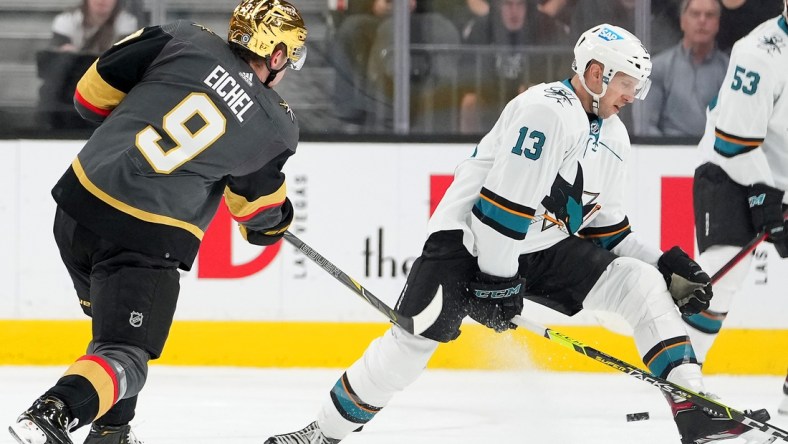 Mar 1, 2022; Las Vegas, Nevada, USA;  Vegas Golden Knights center Jack Eichel (9) shoots through the legs of San Jose Sharks center Nick Bonino (13) during the first period at T-Mobile Arena. Mandatory Credit: Stephen R. Sylvanie-USA TODAY Sports