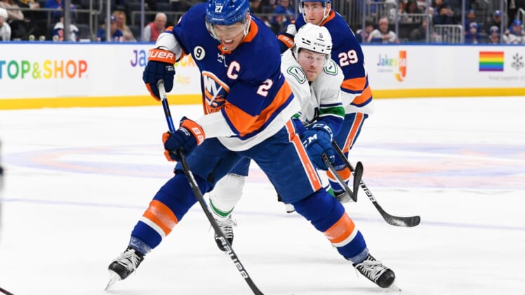 Mar 3, 2022; Elmont, New York, USA; New York Islanders left wing Anders Lee (27) attempts a shot against the Vancouver Canucks during the second period at UBS Arena. Mandatory Credit: Dennis Schneidler-USA TODAY Sports