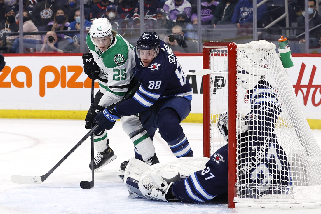 Mar 4, 2022; Winnipeg, Manitoba, CAN; Dallas Stars left wing Joel Kiviranta (25) and Winnipeg Jets defenseman Nate Schmidt (88) dig for the puck under a fallen Winnipeg Jets goaltender Connor Hellebuyck (37) in the first period at Canada Life Centre. Mandatory Credit: James Carey Lauder-USA TODAY Sports