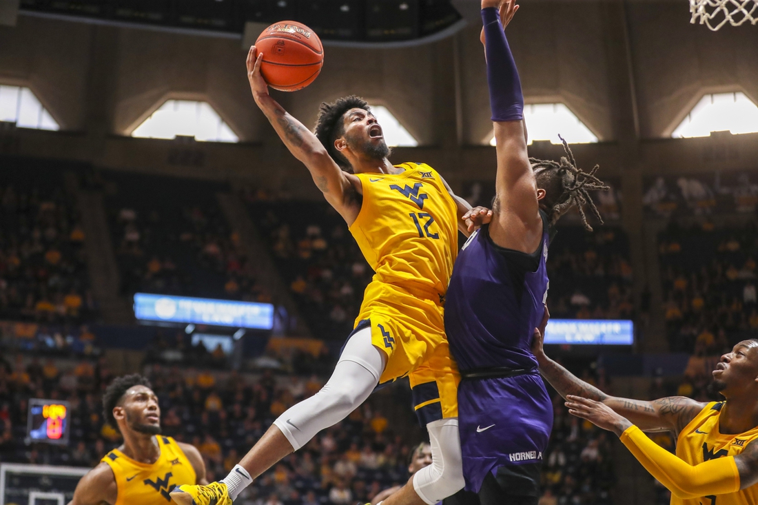 Mar 5, 2022; Morgantown, West Virginia, USA; West Virginia Mountaineers guard Taz Sherman (12) shoots in the lane against TCU Horned Frogs center Eddie Lampkin (4) during the second half at WVU Coliseum. Mandatory Credit: Ben Queen-USA TODAY Sports