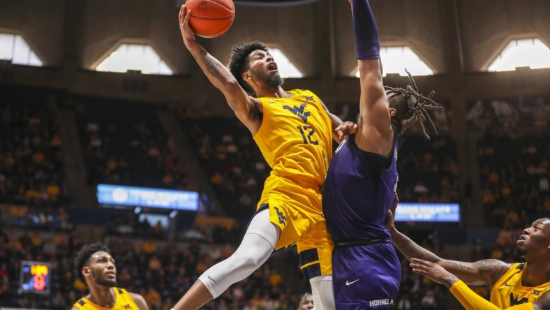 Mar 5, 2022; Morgantown, West Virginia, USA; West Virginia Mountaineers guard Taz Sherman (12) shoots in the lane against TCU Horned Frogs center Eddie Lampkin (4) during the second half at WVU Coliseum. Mandatory Credit: Ben Queen-USA TODAY Sports