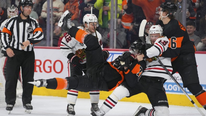 Mar 5, 2022; Philadelphia, Pennsylvania, USA; Chicago Blackhawks center Jonathan Toews (19) pulls Philadelphia Flyers defenseman Rasmus Ristolainen (70) to the ice in the second period at the Wells Fargo Center. Mandatory Credit: Mitchell Leff-USA TODAY Sports