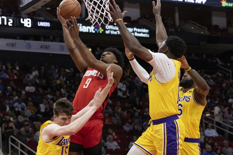 Mar 9, 2022; Houston, Texas, USA;  Houston Rockets guard Josh Christopher (9) scores against Los Angeles Lakers guard Austin Reaves (15) and forward LeBron James (6) in the second quarter at Toyota Center. Mandatory Credit: Thomas Shea-USA TODAY Sports