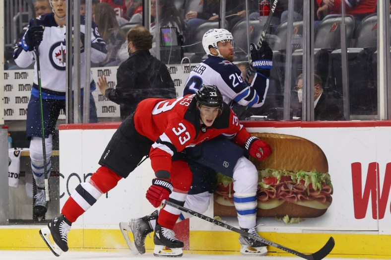 Mar 10, 2022; Newark, New Jersey, USA; New Jersey Devils defenseman Ryan Graves (33) hits Winnipeg Jets right wing Blake Wheeler (26) during the first period at Prudential Center. Mandatory Credit: Ed Mulholland-USA TODAY Sports