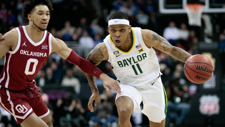 Mar 10, 2022; Kansas City, MO, USA; Baylor Bears guard James Akinjo (11) drives to the basket around Oklahoma Sooners guard Jordan Goldwire (0) during the first half at T-Mobile Center. Mandatory Credit: William Purnell-USA TODAY Sports