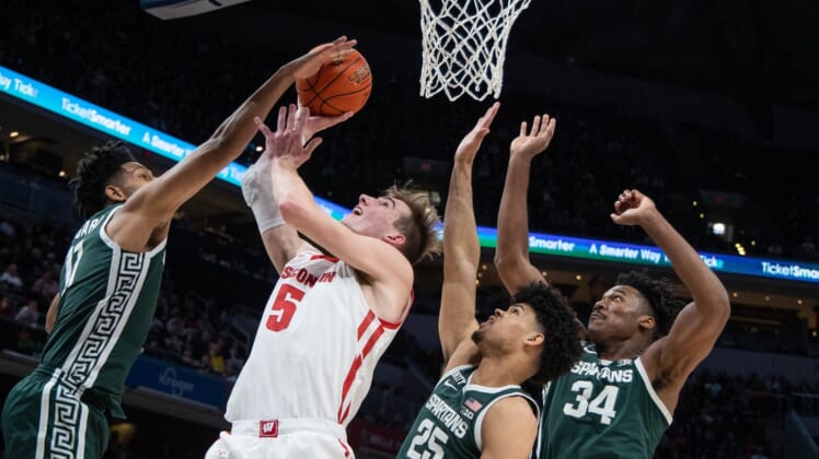 Mar 11, 2022; Indianapolis, IN, USA; Wisconsin Badgers forward Tyler Wahl (5) shoots the ball while Michigan State Spartans guard A.J. Hoggard (11) forward Malik Hall (25) and forward Julius Marble II (34) defend in the first half at Gainbridge Fieldhouse. Mandatory Credit: Trevor Ruszkowski-USA TODAY Sports