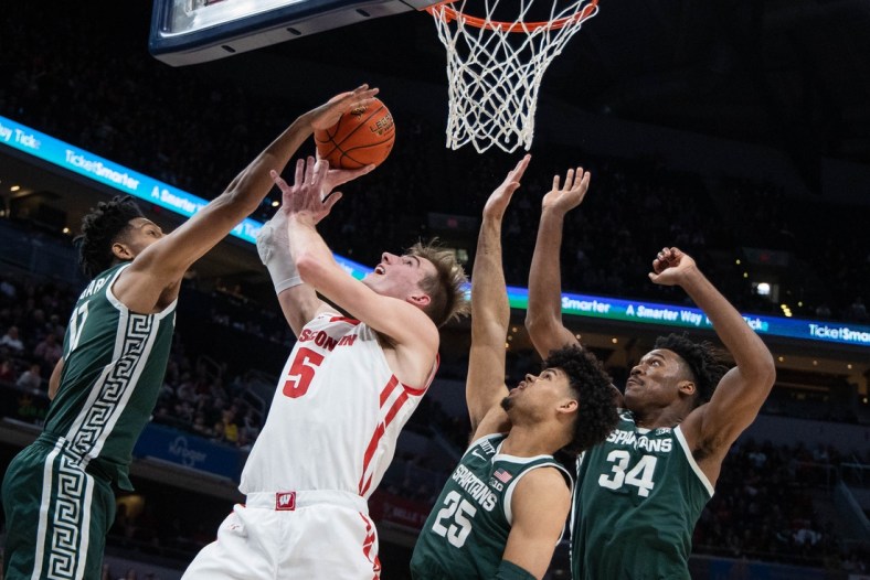 Mar 11, 2022; Indianapolis, IN, USA; Wisconsin Badgers forward Tyler Wahl (5) shoots the ball while Michigan State Spartans guard A.J. Hoggard (11) forward Malik Hall (25) and forward Julius Marble II (34) defend in the first half at Gainbridge Fieldhouse. Mandatory Credit: Trevor Ruszkowski-USA TODAY Sports