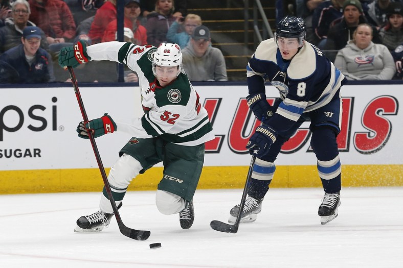 Mar 11, 2022; Columbus, Ohio, USA; Minnesota Wild center Connor Dewar (52) skates around the check of Columbus Blue Jackets defenseman Zach Werenski (8) during the first period at Nationwide Arena. Mandatory Credit: Russell LaBounty-USA TODAY Sports