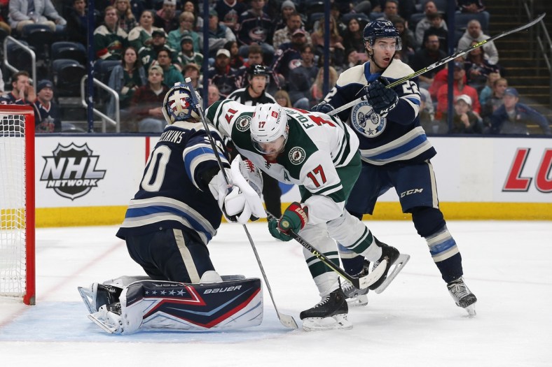 Mar 11, 2022; Columbus, Ohio, USA; Minnesota Wild left wing Marcus Foligno (17) collides with Columbus Blue Jackets goalie Elvis Merzlikins (90) during the third period at Nationwide Arena. Mandatory Credit: Russell LaBounty-USA TODAY Sports