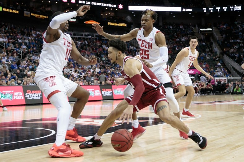 Mar 11, 2022; Kansas City, MO, USA; Oklahoma Sooners guard Jordan Goldwire (0) looks for an opening between Texas Tech Red Raiders forward Bryson Williams (11) and guard Adonis Arms (25) during the first half at T-Mobile Center. Mandatory Credit: William Purnell-USA TODAY Sports