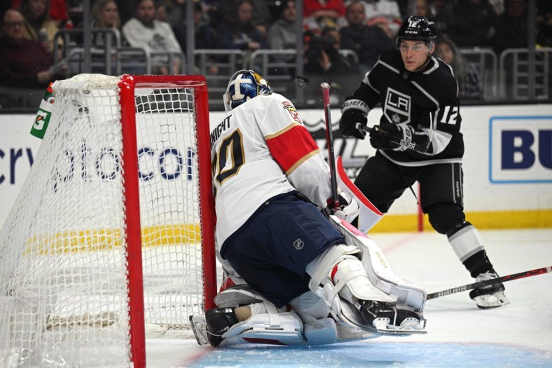 Mar 13, 2022; Los Angeles, California, USA; Florida Panthers goaltender Spencer Knight (30) blocks a shot as Los Angeles Kings left wing Trevor Moore (12) looks on during the second period at Crypto.com Arena. Mandatory Credit: Orlando Ramirez-USA TODAY Sports