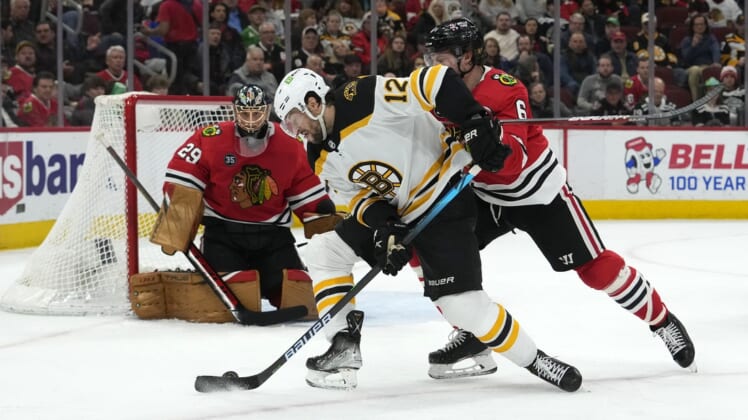 Mar 15, 2022; Chicago, Illinois, USA; Boston Bruins center Craig Smith (12) shoots the puck on Chicago Blackhawks defenseman Jake McCabe (6) during the second period at the United Center. Mandatory Credit: Mike Dinovo-USA TODAY Sports