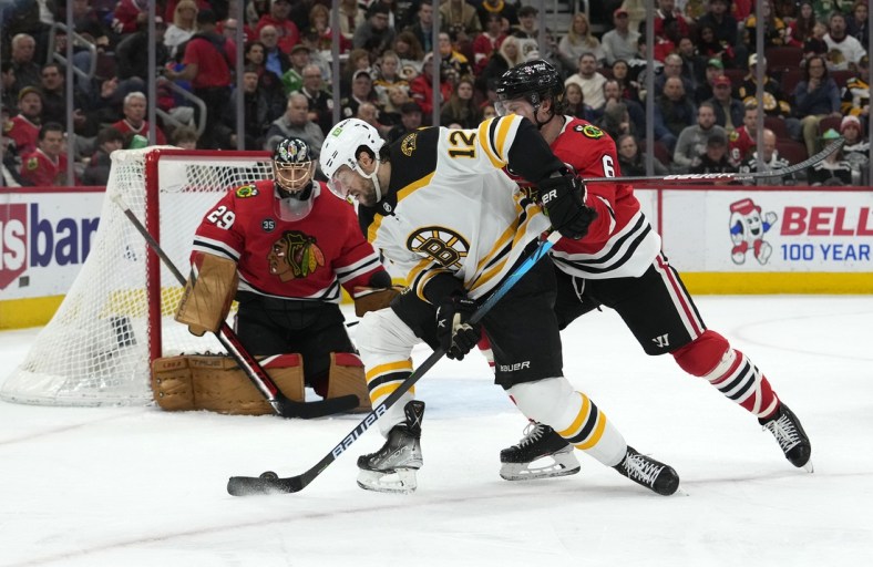Mar 15, 2022; Chicago, Illinois, USA; Boston Bruins center Craig Smith (12) shoots the puck on Chicago Blackhawks defenseman Jake McCabe (6) during the second period at the United Center. Mandatory Credit: Mike Dinovo-USA TODAY Sports