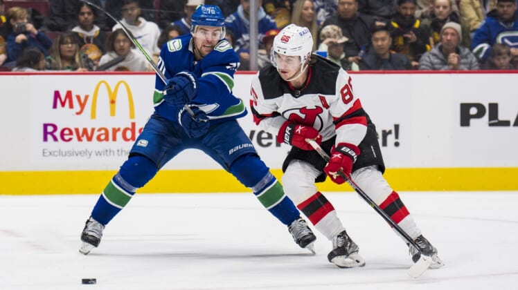 Mar 15, 2022; Vancouver, British Columbia, CAN; Vancouver Canucks forward Tanner Pearson (70) stick checks New Jersey Devils forward Jack Hughes (86) in the second period at Rogers Arena. Mandatory Credit: Bob Frid-USA TODAY Sports