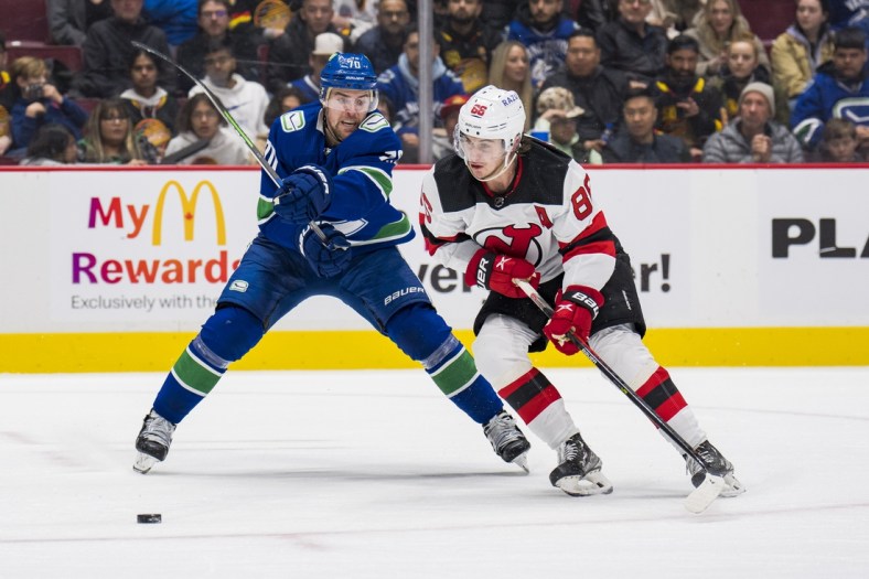 Mar 15, 2022; Vancouver, British Columbia, CAN; Vancouver Canucks forward Tanner Pearson (70) stick checks New Jersey Devils forward Jack Hughes (86) in the second period at Rogers Arena. Mandatory Credit: Bob Frid-USA TODAY Sports