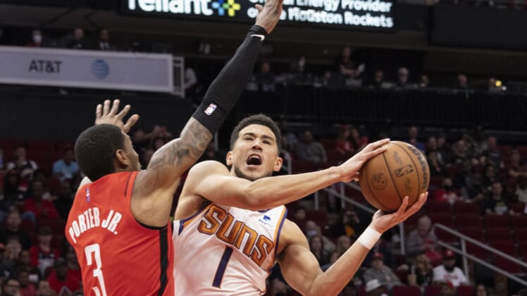 Mar 16, 2022; Houston, Texas, USA; Phoenix Suns guard Devin Booker (1) shoots against Houston Rockets guard Kevin Porter Jr. (3) in the first quarter at Toyota Center. Mandatory Credit: Thomas B. Shea-USA TODAY Sports