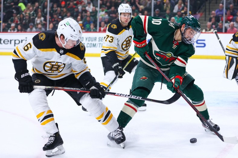 Mar 16, 2022; Saint Paul, Minnesota, USA; Minnesota Wild center Tyson Jost (10) and Boston Bruins defenseman Mike Reilly (6) fight for the puck during the first period at Xcel Energy Center. Mandatory Credit: Harrison Barden-USA TODAY Sports
