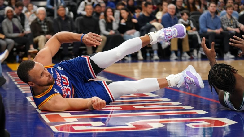 Mar 16, 2022; San Francisco, California, USA; Golden State Warriors guard Stephen Curry (30) falls on the ground after being called for an offensive foul against the Boston Celtics in the second quarter at the Chase Center. Mandatory Credit: Cary Edmondson-USA TODAY Sports