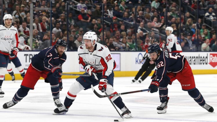 Mar 17, 2022; Columbus, Ohio, USA; Washington Capitals center Evgeny Kuznetsov (92) carries the puck around Columbus Blue Jackets center Sean Kuraly (7) during the first period at Nationwide Arena. Mandatory Credit: Russell LaBounty-USA TODAY Sports