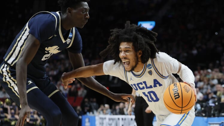 Mar 17, 2022; Portland, OR, USA; UCLA Bruins guard Tyger Campbell (10) dribbles the basketball against Akron Zips center Aziz Bandaogo (21) during the second half during the first round of the 2022 NCAA Tournament at Moda Center. Mandatory Credit: Soobum Im-USA TODAY Sports