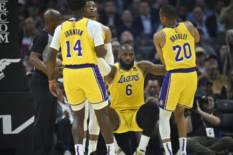Mar 21, 2022; Cleveland, Ohio, USA; Los Angeles Lakers forward LeBron James (6) is helped to his feet by forward Stanley Johnson (14) and guard Avery Bradley (20) in the second quarter against the Cleveland Cavaliers at Rocket Mortgage FieldHouse. Mandatory Credit: David Richard-USA TODAY Sports