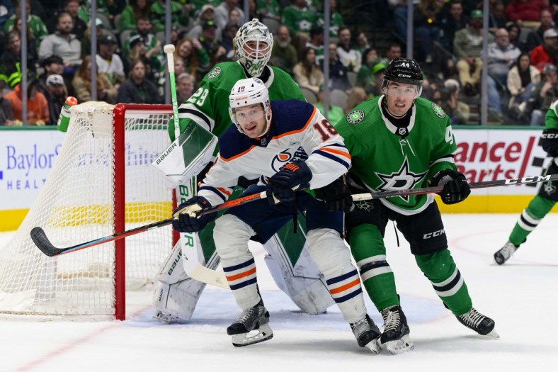 Mar 22, 2022; Dallas, Texas, USA; Edmonton Oilers left wing Zach Hyman (18) and Dallas Stars defenseman Joel Hanley (44) look for the puck during the first period at the American Airlines Center. Mandatory Credit: Jerome Miron-USA TODAY Sports