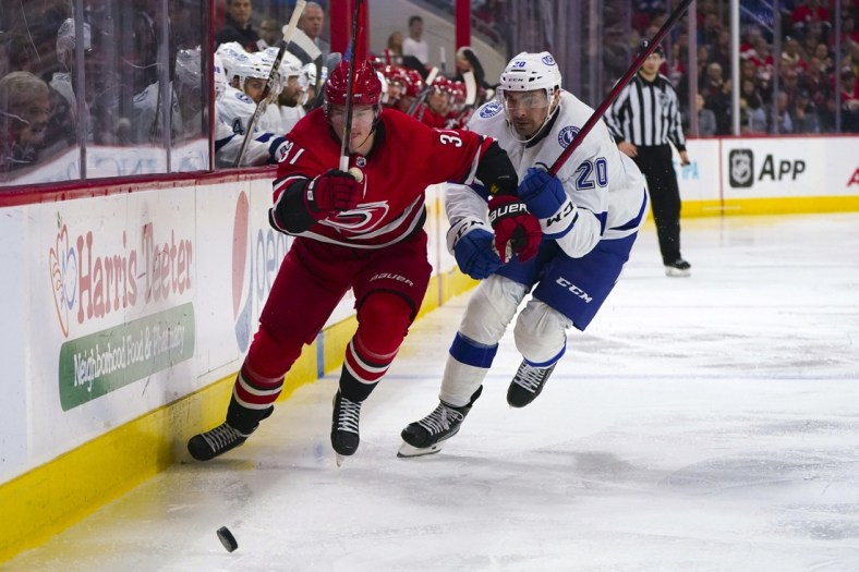 Mar 22, 2022; Raleigh, North Carolina, USA;  Carolina Hurricanes right wing Andrei Svechnikov (37) and Tampa Bay Lightning left wing Nicholas Paul (20) skate after the puck during the third period at PNC Arena. Mandatory Credit: James Guillory-USA TODAY Sports