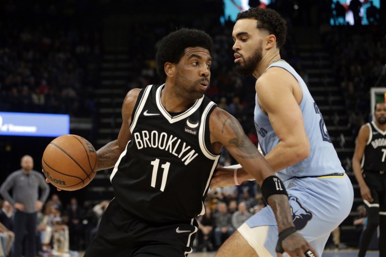 Mar 23, 2022; Memphis, Tennessee, USA; Brooklyn Nets guard Kyrie Irving (11) drives to the basket as Memphis Grizzlies guard Tyus Jones (21) defends during the first half at FedExForum. Mandatory Credit: Petre Thomas-USA TODAY Sports