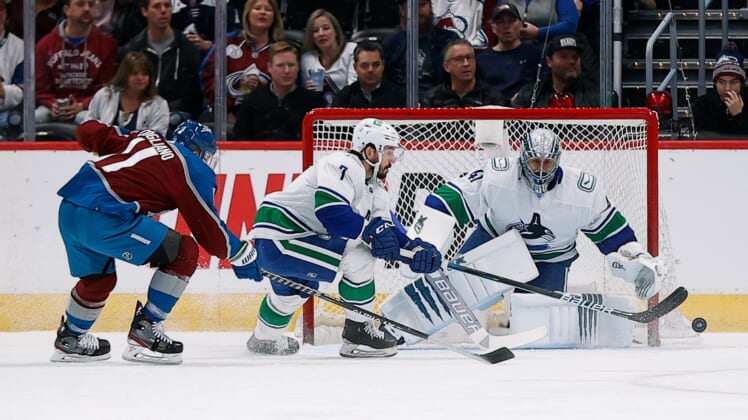 Mar 23, 2022; Denver, Colorado, USA; Vancouver Canucks center Nic Petan (7) and Colorado Avalanche center Andrew Cogliano (11) battle for the puck ahead of goaltender Jaroslav Halak (41) in the first period at Ball Arena. Mandatory Credit: Isaiah J. Downing-USA TODAY Sports
