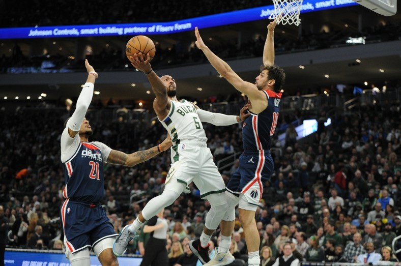 Mar 24, 2022; Milwaukee, Wisconsin, USA; Milwaukee Bucks guard Jevon Carter (5) drives to the basket against Washington Wizards center Daniel Gafford (21) and guard Raul Neto (19) in the first half at Fiserv Forum. Mandatory Credit: Michael McLoone-USA TODAY Sports
