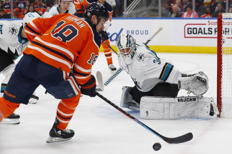 Mar 24, 2022; Edmonton, Alberta, CAN; Edmonton Oilers forward Zach Hyman (18) tries to take a shot on San Jose Sharks goaltender Kaapo Kahkonen (34) during the first period at Rogers Place. Mandatory Credit: Perry Nelson-USA TODAY Sports