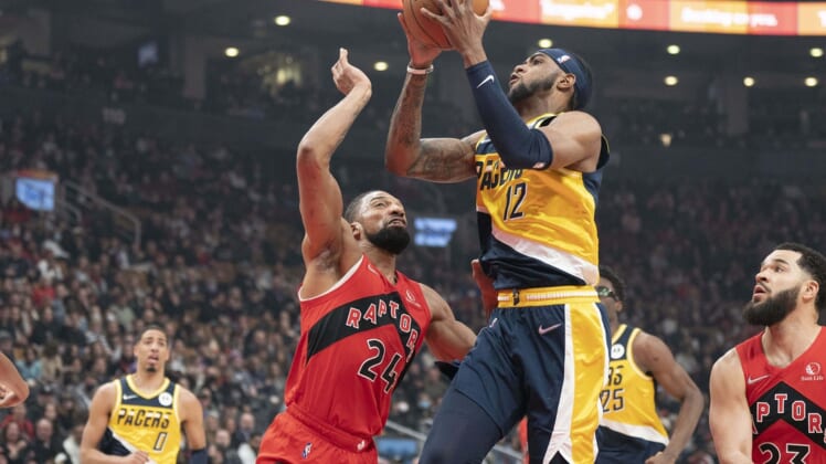 Mar 26, 2022; Toronto, Ontario, CAN; Indiana Pacers forward Oshae Brissett (12) drives to the basket against Toronto Raptors center Khem Birch (24) during the first quarter at Scotiabank Arena. Mandatory Credit: Nick Turchiaro-USA TODAY Sports