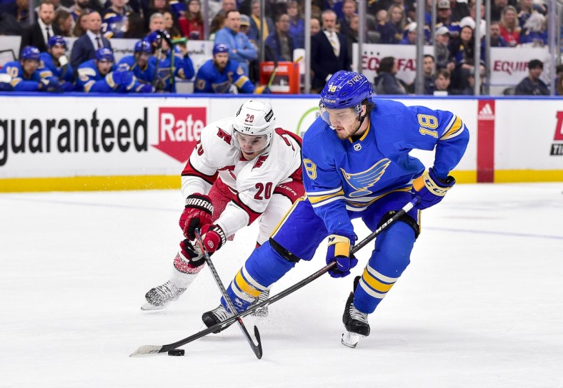 Mar 26, 2022; St. Louis, Missouri, USA;  St. Louis Blues center Robert Thomas (18) and Carolina Hurricanes center Sebastian Aho (20) battle for the puck during the first period at Enterprise Center. Mandatory Credit: Jeff Curry-USA TODAY Sports
