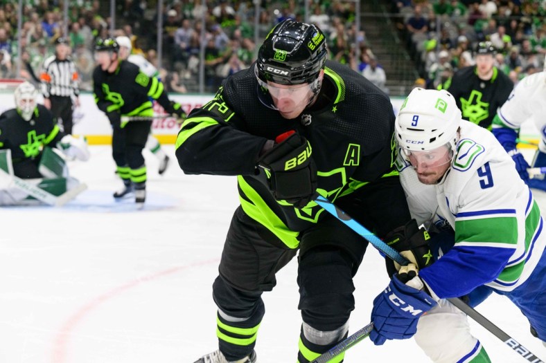 Mar 26, 2022; Dallas, Texas, USA; Dallas Stars defenseman Esa Lindell (23) and Vancouver Canucks center J.T. Miller (9) chase the puck during the third period at the American Airlines Center. Mandatory Credit: Jerome Miron-USA TODAY Sports