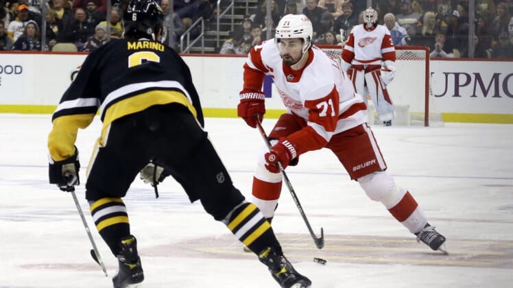 Mar 27, 2022; Pittsburgh, Pennsylvania, USA; Detroit Red Wings center Dylan Larkin (71) moves the puck against Pittsburgh Penguins defenseman John Marino (6) during the third period at PPG Paints Arena. Mandatory Credit: Charles LeClaire-USA TODAY Sports