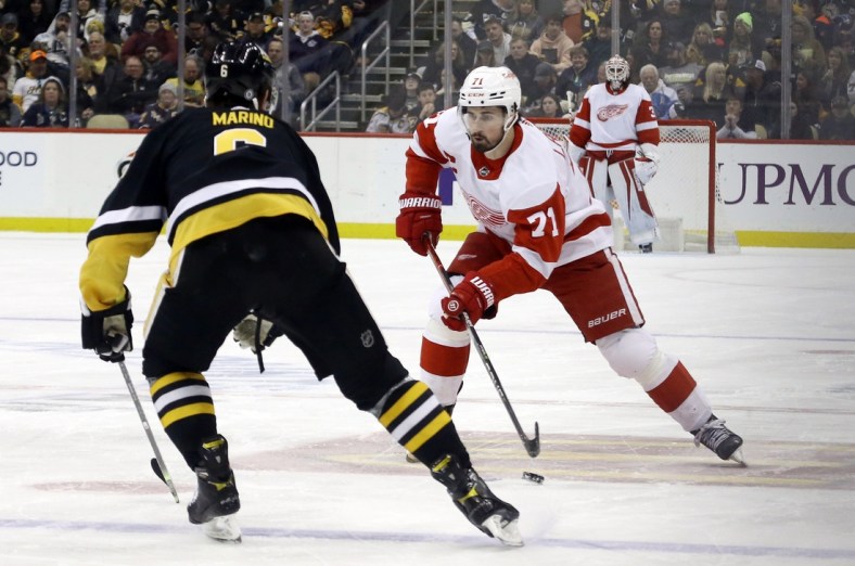Mar 27, 2022; Pittsburgh, Pennsylvania, USA; Detroit Red Wings center Dylan Larkin (71) moves the puck against Pittsburgh Penguins defenseman John Marino (6) during the third period at PPG Paints Arena. Mandatory Credit: Charles LeClaire-USA TODAY Sports