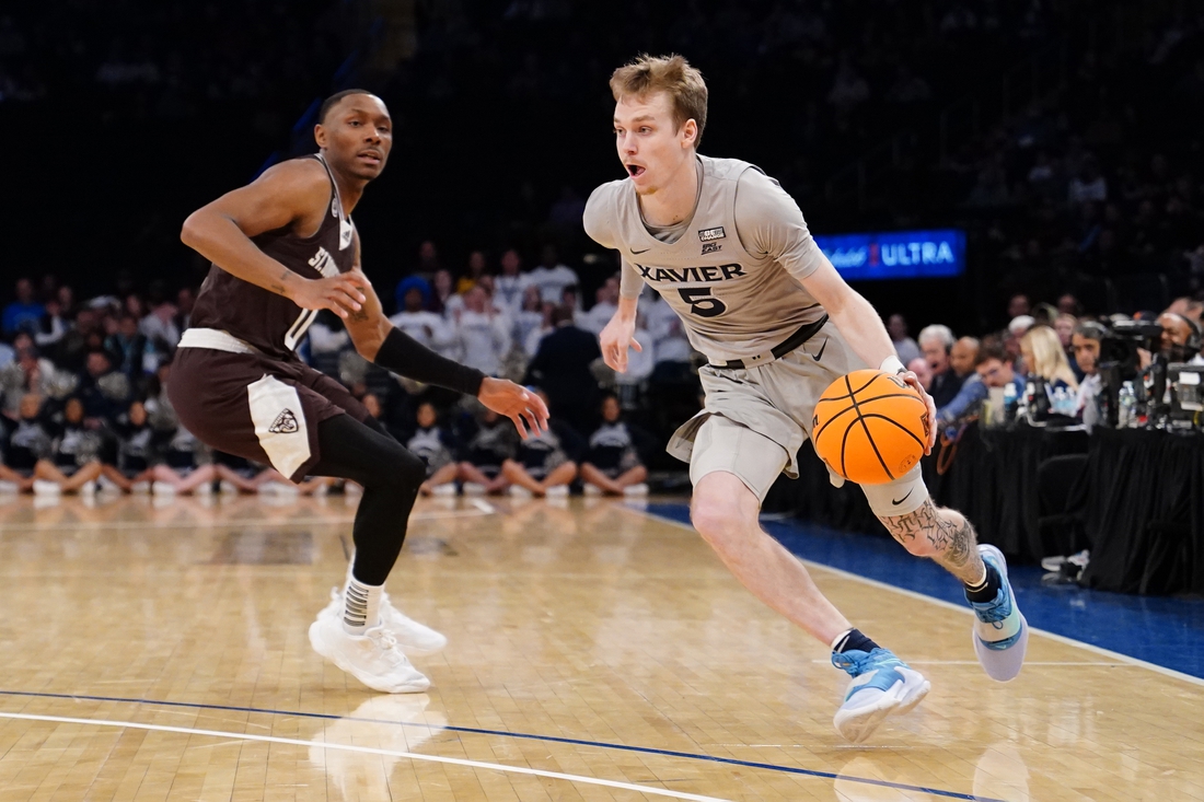 Mar 29, 2022; New York, New York, USA; Xavier Musketeers guard Adam Kunkel (5) dribbles the ball pst St. Bonaventure Bonnies guard Kyle Lofton (0) defending  during the NIT college basketball semifinals at Madison Square Garden. Mandatory Credit: Gregory Fisher-USA TODAY Sports