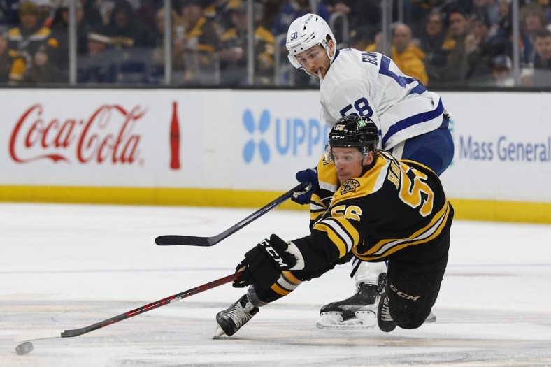 Mar 29, 2022; Boston, Massachusetts, USA; Boston Bruins left wing Erik Haula (56) tries to control a loose puck while going down in front of Toronto Maple Leafs left wing Michael Bunting (58) during the second period at TD Garden. Mandatory Credit: Winslow Townson-USA TODAY Sports