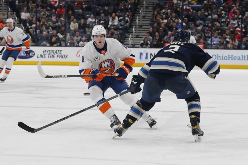 Mar 29, 2022; Columbus, Ohio, USA; New York Islanders defenseman Noah Dobson (8) passes the puck over the sack of Columbus Blue Jackets defenseman Andrew Peeke (2) during the third period at Nationwide Arena. Mandatory Credit: Russell LaBounty-USA TODAY Sports