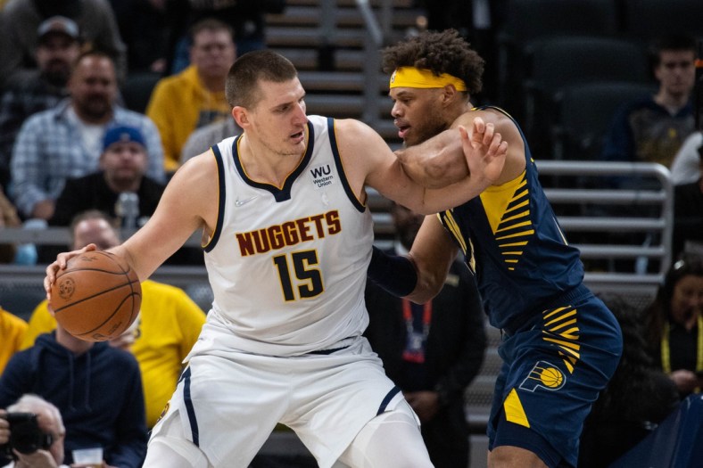 Mar 30, 2022; Indianapolis, Indiana, USA; Denver Nuggets center Nikola Jokic (15) dribbles the ball while Indiana Pacers forward Justin Anderson (10) defends in the second half at Gainbridge Fieldhouse. Mandatory Credit: Trevor Ruszkowski-USA TODAY Sports