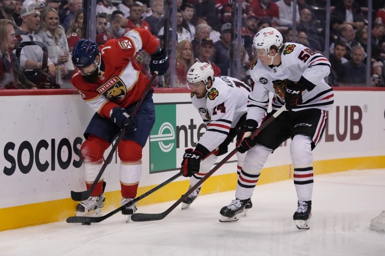 Mar 31, 2022; Sunrise, Florida, USA; Florida Panthers defenseman Radko Gudas (7) plays the puck in front of Chicago Blackhawks left wing Boris Katchouk (14) and right wing MacKenzie Entwistle (58)during the first period at FLA Live Arena. Mandatory Credit: Jasen Vinlove-USA TODAY Sports