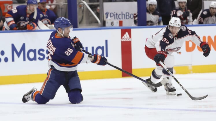 Mar 31, 2022; Elmont, New York, USA;  New York Islanders right wing Oliver Wahlstrom (26) passes the puck from his knees against Columbus Blue Jackets defenseman Jake Bean (22) during the first period at UBS Arena. Mandatory Credit: Thomas Salus-USA TODAY Sports