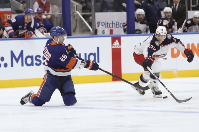 Mar 31, 2022; Elmont, New York, USA;  New York Islanders right wing Oliver Wahlstrom (26) passes the puck from his knees against Columbus Blue Jackets defenseman Jake Bean (22) during the first period at UBS Arena. Mandatory Credit: Thomas Salus-USA TODAY Sports